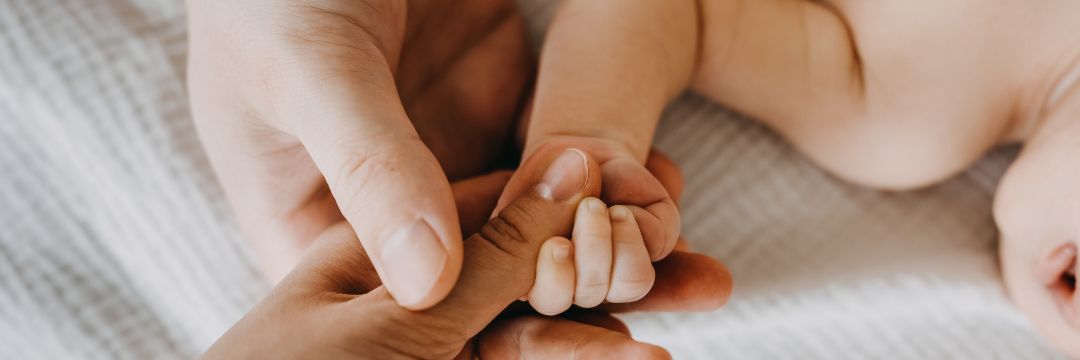 Newborn baby gripping parent's thumb